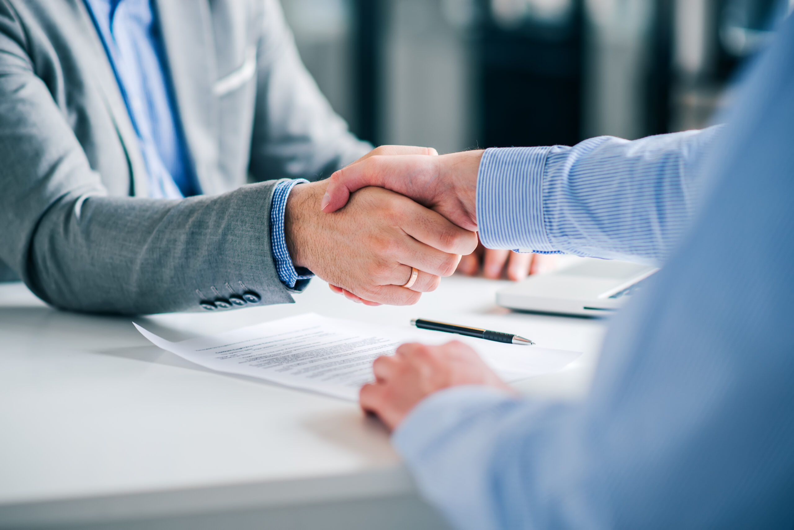 Businessmen handshaking over signed contract.